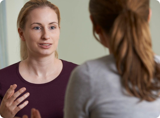 A woman talking to another person in front of a mirror.